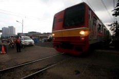  A train heading to Bogor passes a gateless railroad crossing at Roxy, North Jakarta. The crossing is prone to accidents due to the absence of barriers and a warning system and thus, as a temporary solution, the crossing is guarded by a local volunteer. JP/R. Berto Wedhatama