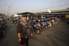A woman passes by a motorcycle parking lot at Rawa Buntu Station, South Tangerang, on Nov. 2, 2015. JP/Dhoni Setiawan