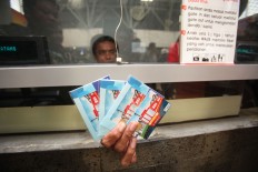 A ticketing counter employee shows off a handful of train tickets. JP/Wendra Ajistyatama