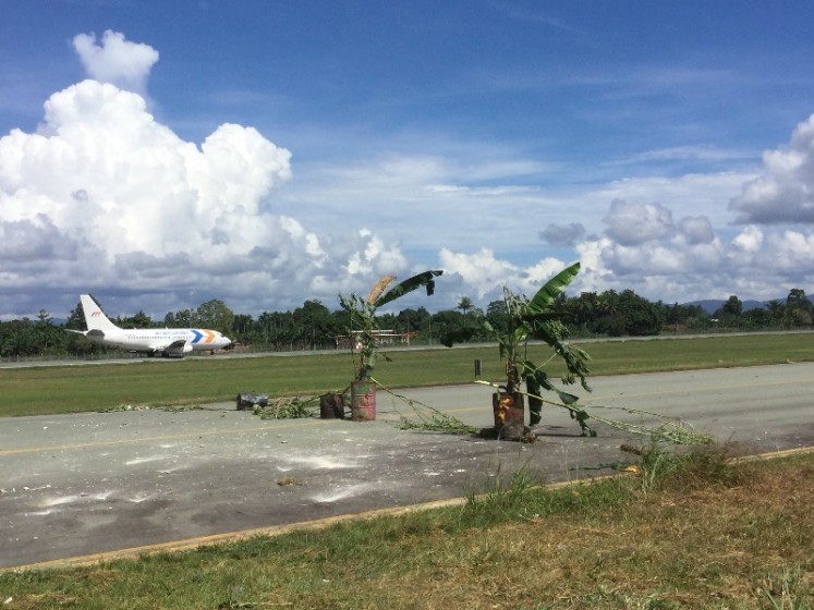 An airplane lands on Sentani Airport in Jayapura, Papua, on May 27, 2016, as banana stems in drums block a taxi way. People from four tribes, the Taime, Yoku, Kopeu and Pallo, blocked the taxi way as they demand compensation of customary land ownership (ulayat) of Rp 156 billion (US$9.6 million) to the airport authorities.