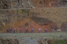 Cyclists speed past a cut-through hill.  ANTARA FOTO/Wahyu Putro A