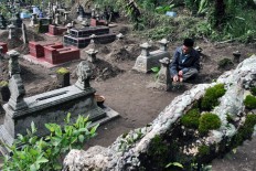 A man recites prayers at the grave of one of his ancestors. The Jakarta Post/ Albertus Magnus Kus Hendratmo