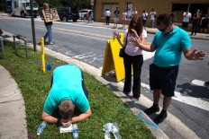 From left, Jeremy Dubach, Gigi Greaves and Joe Greaves pray for victims a few blocks from a crime scene at the nightclub where a mass shooting took place the night before in Orlando, Fla., Sunday, June 12, 2016. A gunman opened fire inside the gay nightclub early Sunday, killing at least 50 people before dying in a gunfight with SWAT officers, police said. Loren Elliott/Tampa Bay Times via AP

