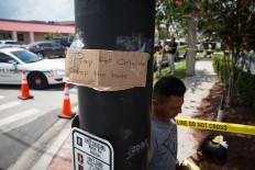 People pass a sign is taped up at an intersection a few blocks from a crime scene at the nightclub where a mass shooting took place the night before in Orlando, Fla., Sunday, June 12, 2016. A gunman opened fire inside the gay nightclub early Sunday, killing at least 50 people before dying in a gunfight with SWAT officers, police said. Loren Elliott/Tampa Bay Times via AP