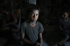 Bangladeshi boy Imran, 11, looks towards camera as he works at a factory that makes metal utensils in Dhaka, Bangladesh, Sunday, June 12, 2016. He earns less than $5 per week. AP Photo/ A.M. Ahad