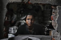 Bangladeshi boy Rubel, 12, looks towards camera as he works at a factory that makes metal utensils in Dhaka, Bangladesh, Sunday, June 12, 2016. He earns less than $5 per week. AP Photo/ A.M. Ahad