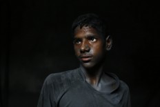 In this Sunday, June 12, 2016, photo, Ridoy, 11, poses for a portrait as he works at a factory that makes metal utensils in 
Dhaka, Bangladesh. AP Photo/ A.M. Ahad
