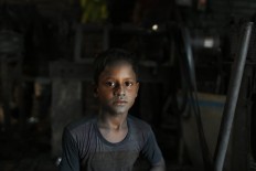 In this Sunday, June 12, 2016, photo, Bangladeshi child Arif, 9, looks towards camera as he works at a factory that makes metal utensils in Dhaka, Bangladesh. AP Photo/ A.M. Ahad