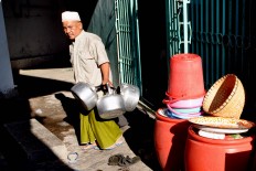 A staffer at Pekojan Jami’ mosque carries three kettles to make milk beverages. JP/ Albertus Magnus Kus Hendratmo