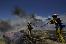 Firefighters put out a spot fire as they continue to battle a wildfire burning along Highway 178 near Lake Isabella, Calif., Friday, June 24, 2016. The wildfire that roared across dry brush and trees in the mountains of central California gave residents little time to flee as flames burned homes to the ground, propane tanks exploded and smoke obscured the path to safety. AP Photo/Jae C. Hong