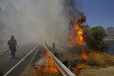 A firefighter battles a wildfire burning along Highway 178, Friday, June 24, 2016 in Lake Isabella, Calif. The wildfire that roared across dry brush and trees in the mountains of central California gave residents little time to flee as flames burned homes to the ground, propane tanks exploded and smoke obscured the path to safety. AP Photo/Jae C. Hong