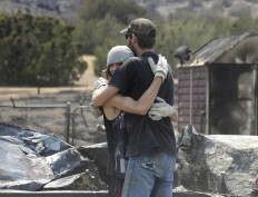 Lucas Martin, right, hugs his stepson, Nathan Looper, after finding an heirloom belt buckle he thought was destroyed at his home in South Lake, Calif. The buckle belonged to Martin's best friend who had left it at the home when he went to work on the day the home was burned down. AP Photo/Rich Pedroncelli