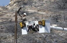 Robert Delgado, a lineman for Southern California Edison, works on power line at fire ravaged South Lake, Calif., Monday, June 27, 2016. Power crews work restore power to the area that was swept by fire near Lake Isabella, Calif. The fire that started Thursday, has taken the lives of an elderly couple, apparently overcome by smoke, burned more than 70 square miles, and is 40 percent contained. AP Photo/Rich Pedroncelli