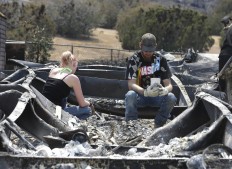 Lucas Martin stares at a cup found in the ashes of his fire ravaged home in South Lake, Calif., Sunday, June 26, 2016. Martin's home was among the more than 200 homes and buildings destroyed by the fire that swept through the area near Lake Isabella, Calif. At right is Emily Fryer who help Martin sift through the rubble. AP Photo/Rich Pedroncelli

