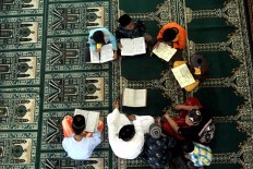 Several children take turns reciting the Quran to complete the full reading before breaking the fast as part of the Megibung tradition ceremony at the Muhajirin Mosque in Kepaon muslim village in Denpasar, Bali, on June 15.  JP/Zul Trio Anggono