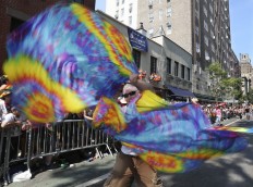A dancer spins colorful scarves in front of the historic Stone Wall Inn during the New York City Pride Parade Sunday, June 26, 2016, in New York. A year after New York City's storied gay pride parade celebrated a high point with the legalization of gay marriage nationwide, the atmosphere this year couldn't be more different. Parades in New York and other major cities Sunday will feature increased security, anti-violence messages and tributes to those killed in this month's massacre at a gay nightclub in Florida. AP Photo/Mel Evans