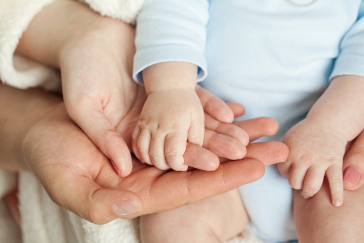 An infant's hands are held next to adult hands in this undated illustration. 
