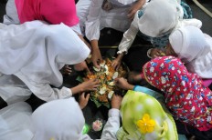 Young students eat Nasi Tumpeng, cone-shaped yellow rice, before the Quran recital begins. JP/Ganug Nugroho Adi