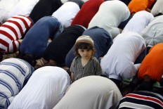 A child sits among men during the Eid al-Fitr prayers, in the southern port city of Sidon, Lebanon, Wednesday, July 6, 2016. Eid al-Fitr marks the end of the Muslim fasting month of Ramadan. AP Photo/Mohammed Zaatari