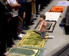 A boy plays on some prayer rugs before the Eid al-Fitr prayer service at Honda Center on Wednesday, July 6, 2016, in Anaheim, Calif. More than 5,000 Muslims attended the Eid Mudarak prayers on Wednesday morning. The event was put on by the Islamic Institute of Orange County. Bill Alkofer/The Orange County Register via AP

