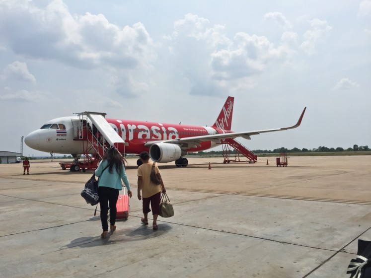 Passengers cross the tarmac to board an AirAsia plane on June 5, 2016, at Khon Kaen International Airport in Thailand.
