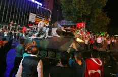 Supporters of Turkish President Recep Tayyip Erdogan ride a police personnel carrier as people gather in Kizilay Square to protest against a military coup in Ankara, Turkey, early Saturday, July 16, 2016. Erdogan told the nation Saturday that his government was working to crush a coup attempt after a night of explosions, air battles and gunfire across the capital. AP Photo/Burhan Ozbilici