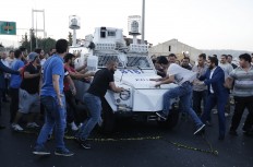 People attack and try to stop a Turkish police armored vehicle, carrying Turkish soldiers that participated in the coup and surrendered, backdropped by Istanbul's iconic Bosporus Bridge, Saturday, July 16, 2016.  Turkish President Recep Tayyip Erdogan told the nation Saturday that his government is in charge after a coup attempt brought a night of explosions, air battles and gunfire across the capital of Ankara. AP Photo/Emrah Gurel