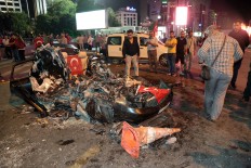 People watch a damaged car which was crashed by a tank in Kizilay Square as they gather to protest against a military coup in Ankara, Turkey, early Saturday, July 16, 2016. Turkish President Recep Tayyip Erdogan told the nation Saturday that his government was working to crush a coup attempt after a night of explosions, air battles and gunfire across the capital. AP Photo/Burhan Ozbilici