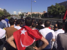 People with the Turkish national flags gather outside the military headquarters in Ankara, Turkey, Saturday July 16, 2016. Turkish President Recep Tayyip Erdogan declared he was in control of the country early Saturday as government forces fought to squash a coup attempt during a night of explosions, air battles and gunfire that left dozens dead. AP Photo/Burhan Ozbilici