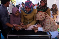 Puskemas Ciracas' staff administers vaccines to a child in East Jakarta, Monday July 18, 2016.