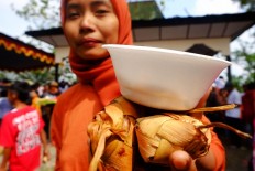 A resident holds up her ketupat and opor ayam. JP/Ganug Nugroho Adi