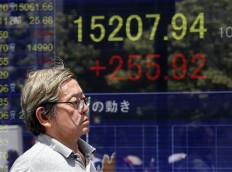 A man walks by an electronic stock board of a securities firm in Tokyo, on June 27, 2016.