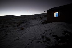In this July 9, 2016 photo, light shines from a home's window in the late afternoon amid fields of snow in San Antonio de Putina in the Puno region of Peru, an area where locals raise alpaca and sheep for their wool. Every winter freeze destroys the tough grasslands the animals feed on and almost no crops can survive in the nutrient-poor soil. AP Photo/Rodrigo Abd