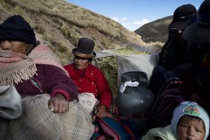 In this July 10, 2016 photo, camelid breeders ride in the back of a pick-up tuck with cooking gas and oats for their alpacas and sheep, as they return to their village of San Antonio de Putina in the Puno region of Peru. The passengers got the 30 minute ride from the nearest town of Cambria to their town from a friend since they don't own their own vehicle, the case of most locals. AP Photo/Rodrigo Abd