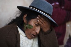 In this July 10, 2016 photo, Valeria Chuquibanca holds her head as she suffers a headache triggered by the heat reflected from the snow, one day after a heavy snow in San Antonio de Putina in the Puno region of Peru. Valeria said that sticking coca leaves near her eyes helps alleviate the pain. AP Photo/Rodrigo Abd