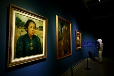 A visitor looks at a row of three historical paintings from the palace collection. The Jakarta Post/Wienda Parwitasari
