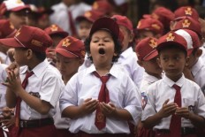 Elementary school students pray together on the first day of school at the Elementary School SDN Simomulyo V, Surabaya in East Java on July 18.