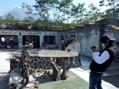 A tourist photographs a destroyed motorcycle at the museum. JP/ Agus Maryono