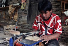 A worker, wearing a T-shirt with a pattern evocative of Eddie van Halen’s iconic tri-color guitar, cuts a guitar body for a Gibson Les Paul miniature in a workshop owned by local entrepreneur Pramono, 42 in Klaten, Central Java. JP/ Albertus Magnus Kus Hendratmo