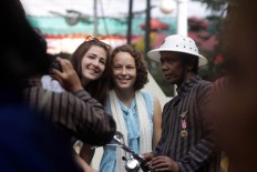 Two foreign tourists pose for a picture with a member of bicycle community Paguyuban Onthel Djogjakarta (Podjok) after an Independence Day ceremony at Bentara Budaya Yogyakarta. JP/ Aditya Sagita