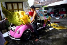 Tono and his wife make decorations for their pedal car for the carnival on Aug. 13. JP/ Aditya Sagita
