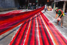 Workers sprinkle color enhancer on batik cloths drawn using the “colet” painting technique. JP/Ganug Nugroho Adi