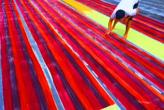 A man checks on a batik cloth after it is painted with colors. JP/Ganug Nugroho Adi