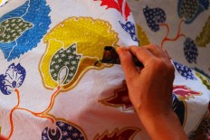 A batik artisan draws a motif on a cloth using a tool called a "canting". JP/Ganug Nugroho Adi.