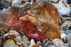 A red section of rock is seen on a beach on Pulau Merah. JP/Tarko Sudiarno