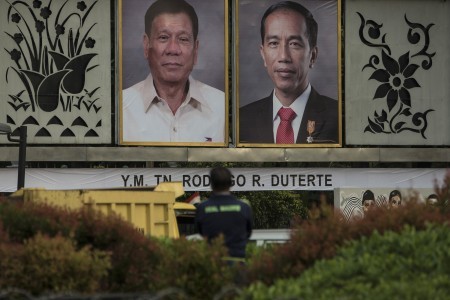 A worker stands in front of photos of President Joko "Jokowi" Widodo and Philippine President Rodrigo Duterte across from the State Palace on Sept. 9. Jokowi will take Duterte to Indonesia's famous textile market Tanah Abang before officially welcoming him at the State Palace on Friday afternoon.