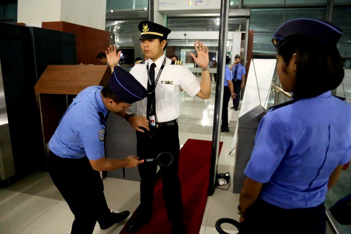 An airport security officer conducts a regular body search on a passenger at Terminal 3 at Soekarno-Hatta International Airport in Tangerang, Banten on Aug. 9, 2016. 
