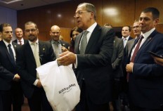 Russian Foreign Minister Sergei Lavrov, center, delivers vodka to reporters awaiting a late night press conference along with U.S. Secretary of State John Kerry in Geneva, Switzerland, on Sept. 9, 2016.