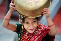 A young Nepalese girl wearing traditional attire plays with a vessel while waiting for the Kumari puja to start at Hanuman Dhoka temple, in Kathmandu, Nepal, Wednesday, Sept. 14, 2016.  AP Photo/Niranjan Shrestha