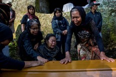 Relatives cry as a coffin containing the corpses of Tikurara, Dumak and Limbongbuak arrive at a cliff-face grave called "liang" in Barrupu village, Toraja, South Sulawesi. JP/Agung Parameswara
